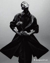 Monochrome portrait of model Min Seok Choi in a flared dark coat holding a flower for an Esquire Korea editorial.