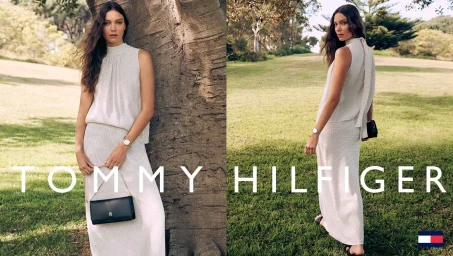 Model wearing a white sleeveless top and skirt leaning against a tree in a park for Tommy Hilfiger