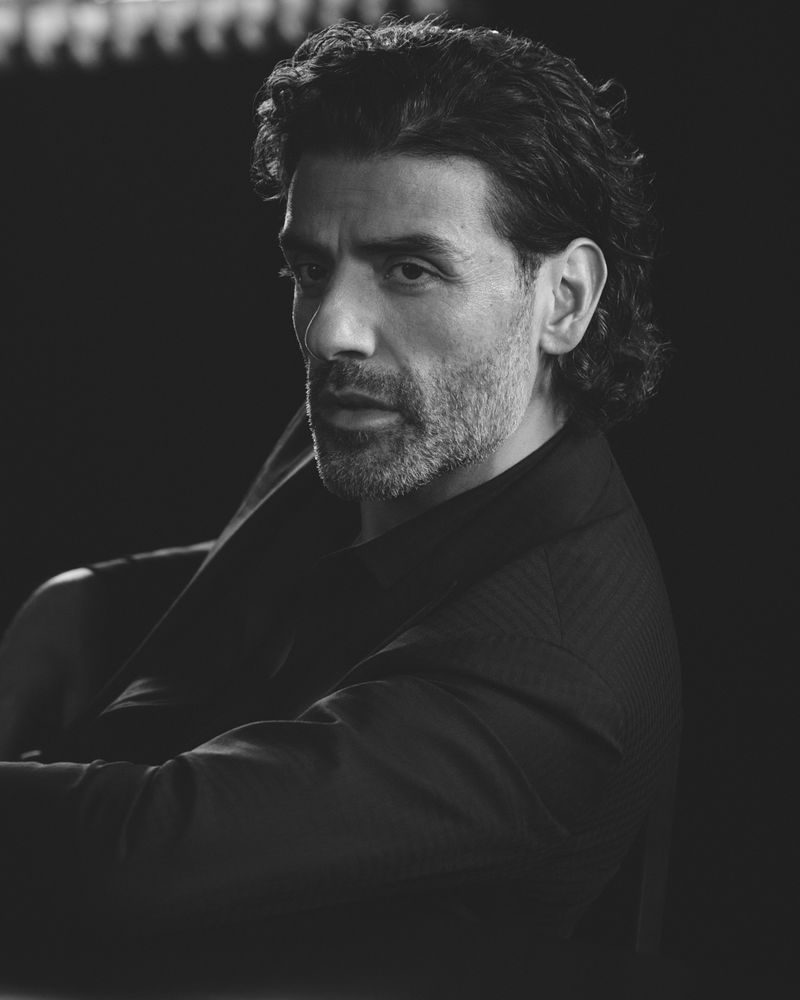Black and white portrait of an adult male with dark hair and a beard, wearing a dark shirt and looking off to the side.