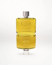 Two stacked Gucci Guilty fragrance bottles with yellow liquid and silver caps against a white seamless background