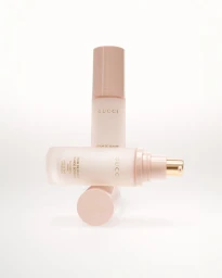 Two Gucci Beauty serum bottles and a cap stacked vertically against a plain white studio background.
