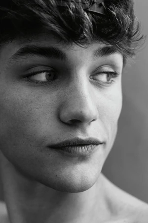 Close-up monochrome portrait of a young man with dark hair looking to the side against a plain background
