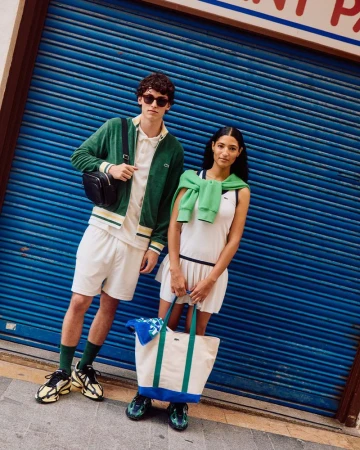 Two fashion models in tennis outfits pose in front of a blue shutter door in natural light, showcasing sport and lifestyle fashion.