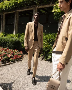 Four male models in tailored menswear walking along a gravel garden path for the Tod's SS24 collection campaign.