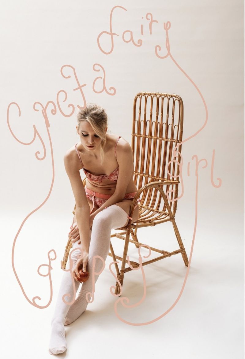 Blonde woman in lingerie sits on a cane chair holding a peach in a studio setting with artistic text effects, creating a dreamy aesthetic.