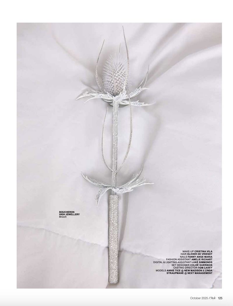 Close-up studio shot of a decorative thistle flower on a wrinkled white cloth backdrop, exhibiting a monochromatic color scheme.