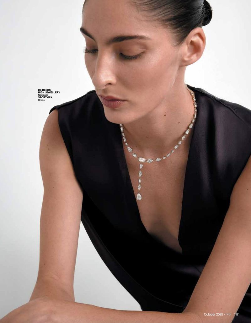 Close-up of a woman with dark hair wearing a black dress and diamond necklace, posing in a photo studio. Beauty shot, fashion concept.