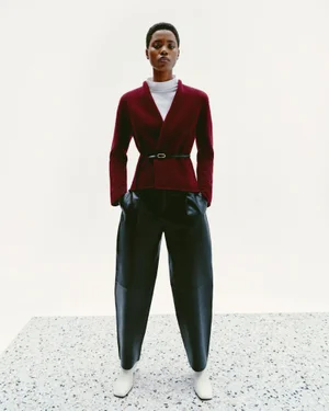 Model Victoria Fawole wears a belted burgundy cardigan and wide black leather trousers on terrazzo flooring for Zara.