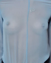Close-up portrait of a model wearing a sheer light blue long-sleeve top with a center seam and delicate necklace.
