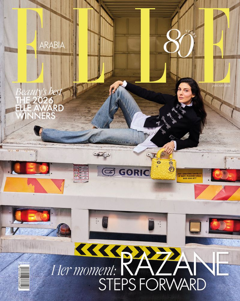 Elle Arabia magazine cover featuring a woman in a black jacket and jeans, lying on the back of a truck, holding a yellow purse.