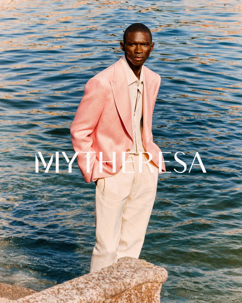 Fashionable man in a pink blazer standing by the water. Stylish adult male model poses outdoors wearing a fashionable blazer and slacks.