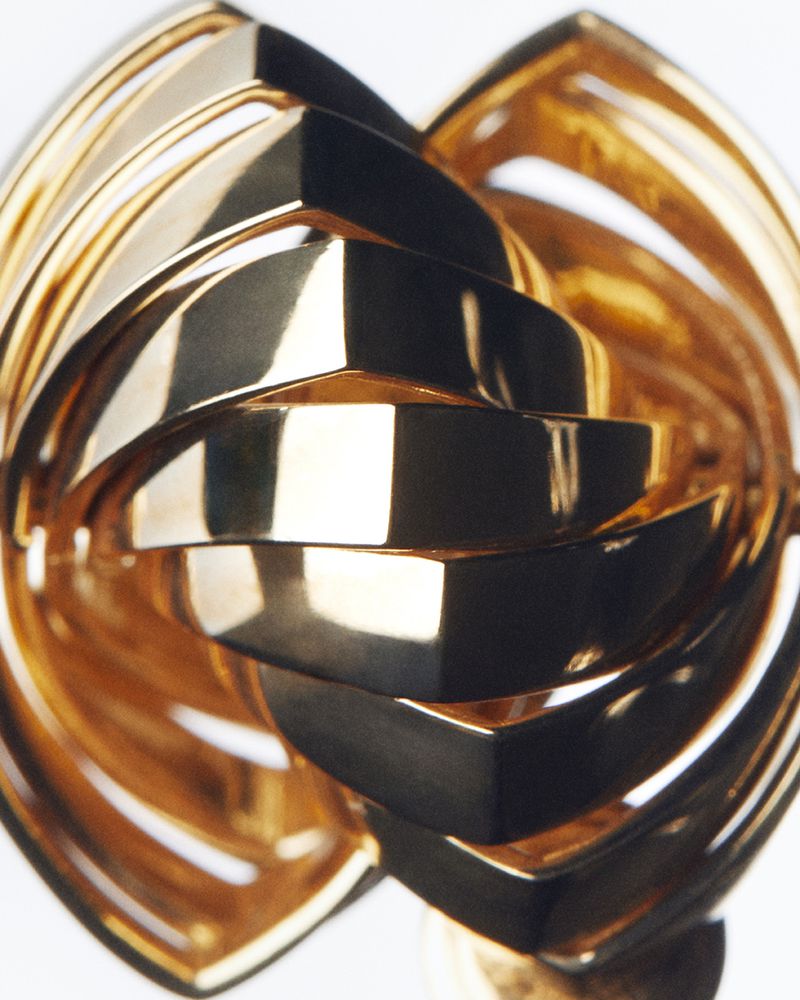 Abstract gold metal sculpture with geometric layers, flowing curves, and a glossy finish, creating an elegant and eye-catching design piece.