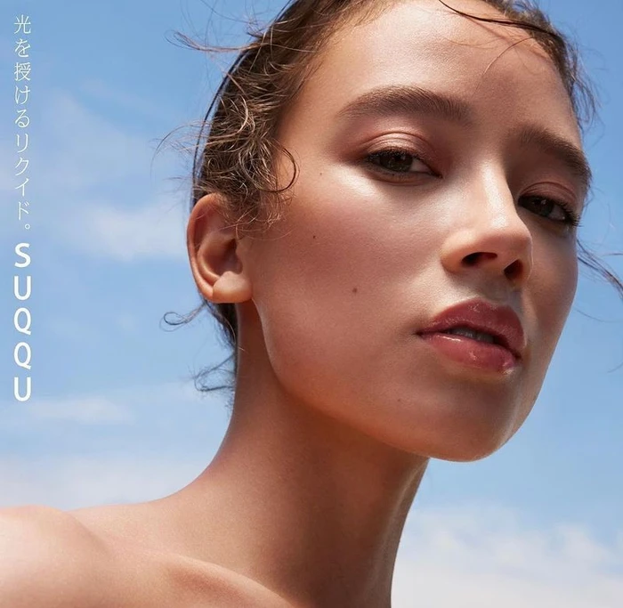 Close-up beauty portrait of a woman with dewy skin against a clear blue sky background for SUQQU
