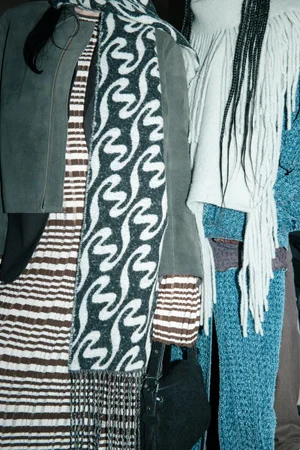 Close-up portrait of two models wearing patterned knitwear and textured outerwear for Holzweiler AW24 collection