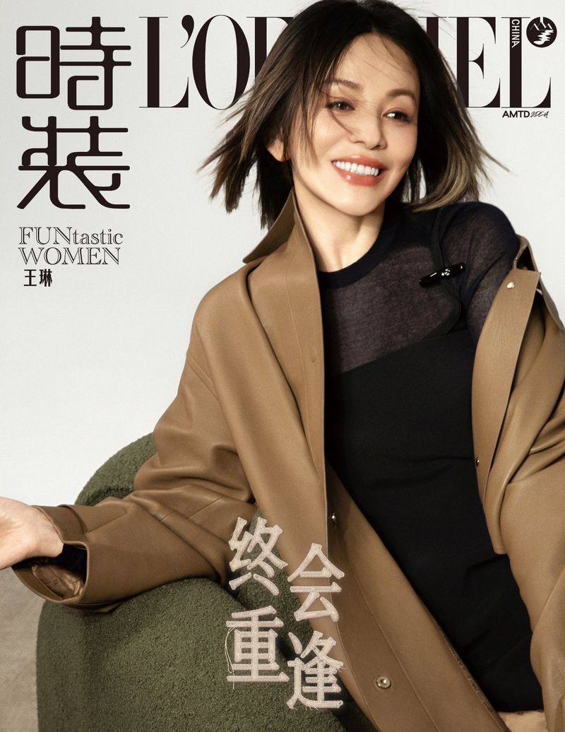 Smiling woman in brown coat and black top sitting on a green armchair for a magazine cover shoot