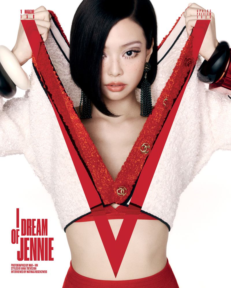 Close-up studio shot of a fair-skinned woman with black hair wearing a white crop top with red trim and large black earrings.