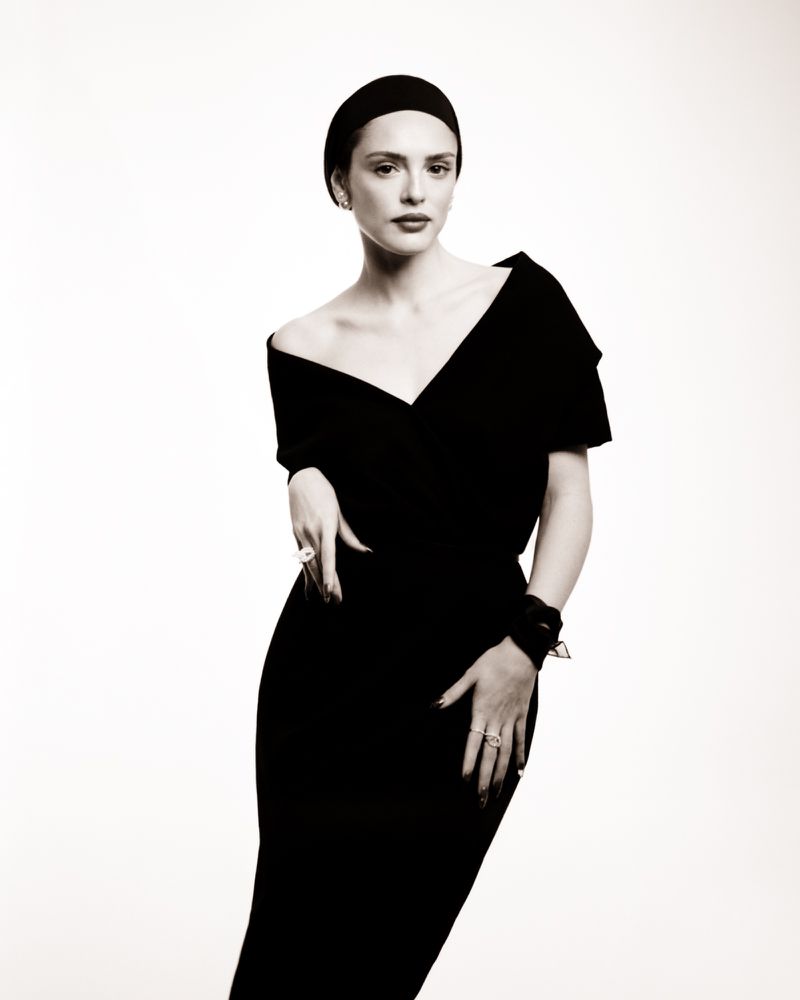 Monochrome portrait of a woman in a black dress and head wrap against a white background, showcasing fashion and studio photography.