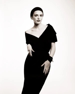 Woman wearing a black dress and headband posing against a bright white background for Miss Dior campaign