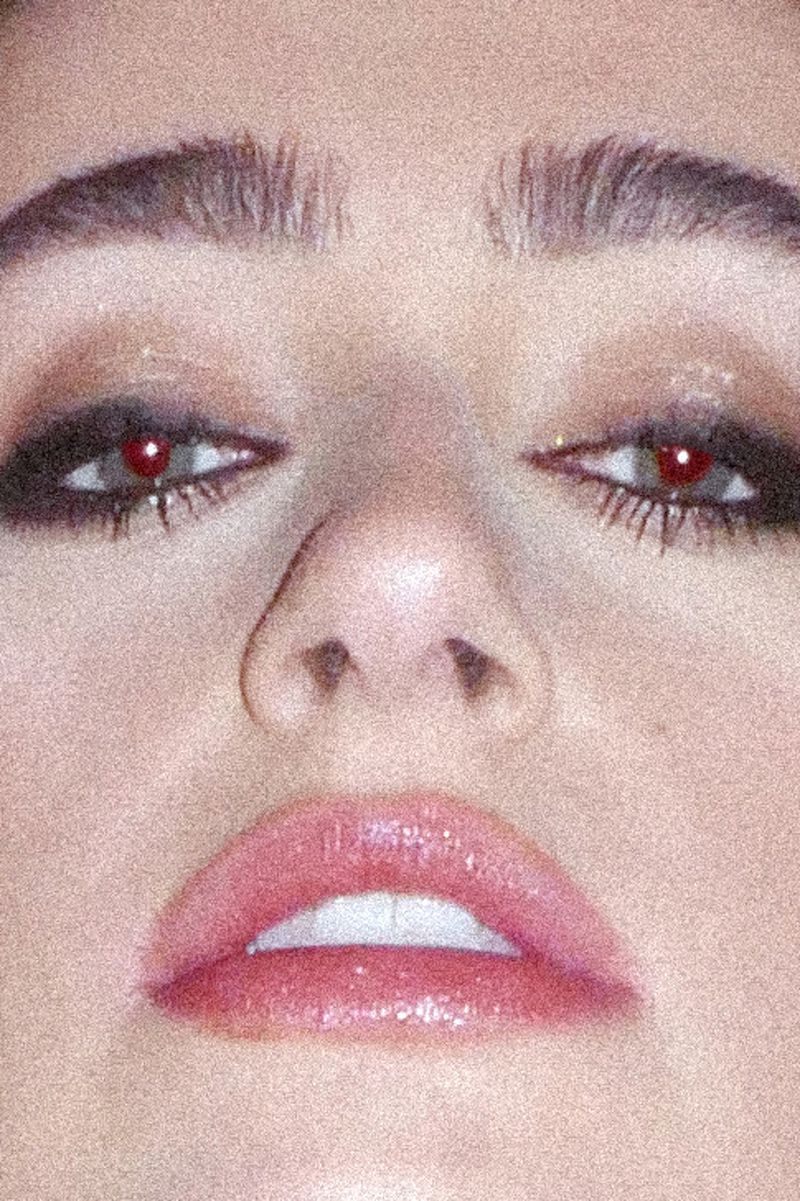 Close-up portrait showcasing a young woman's face featuring prominent eyes with dark eye makeup, a well-defined nose, and full, glossy lips.