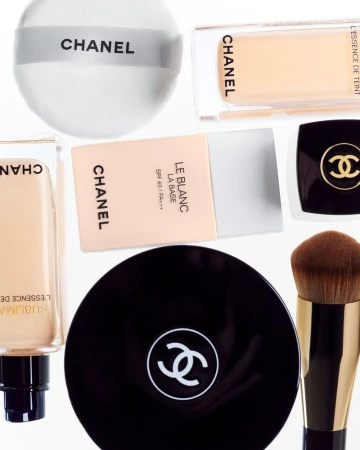 A collection of Chanel brand makeup products are displayed on a white background, showcasing foundation and powder compacts with logo.