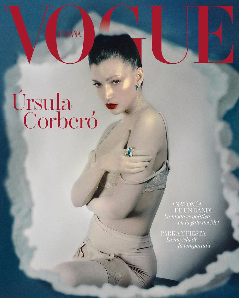 Vogue España cover featuring model Ursula Corbero with red lips, wearing lingerie and jewelry, set against a soft blue background.