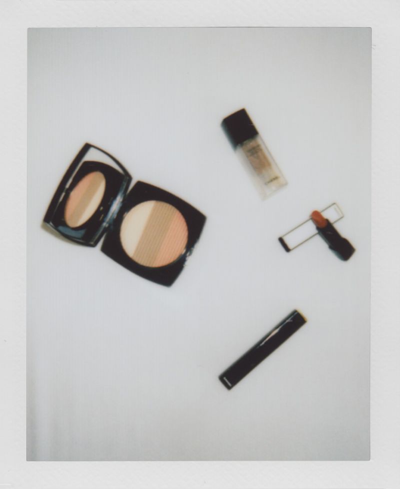 Overhead shot of face makeup, including powder compact, lipstick and foundation, on a white surface, simple product photography.