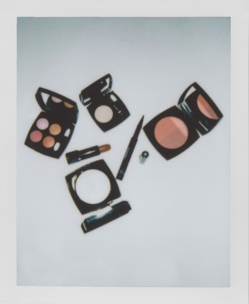 Eye shadow palettes, lipstick, and eyeliner are arranged on a white surface in a beauty still life, capturing cosmetic essentials.