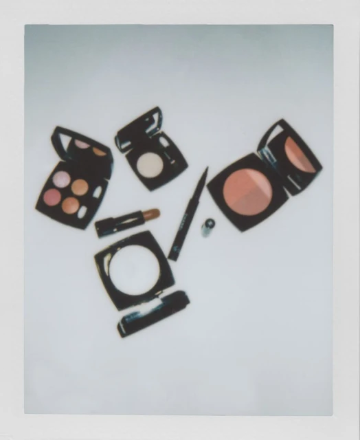 Eye shadow palettes, lipstick, and eyeliner are arranged on a white surface in a beauty still life, capturing cosmetic essentials.