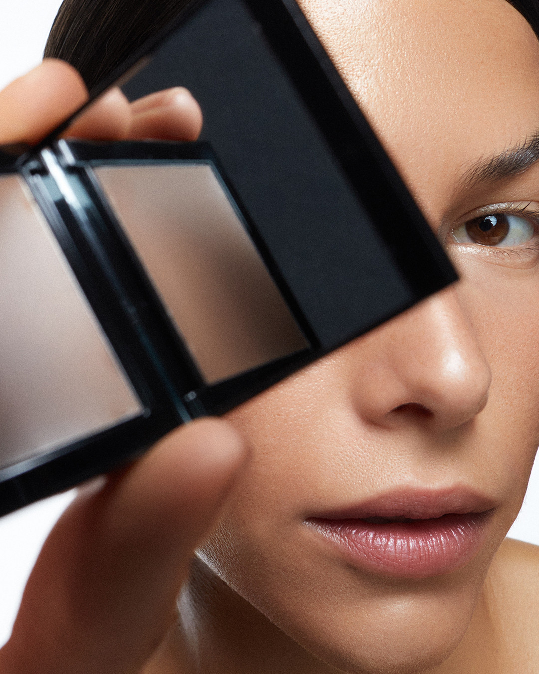 Close-up shot of a woman holding a makeup palette with neutral tones, focusing on beauty, skincare, and cosmetic product.