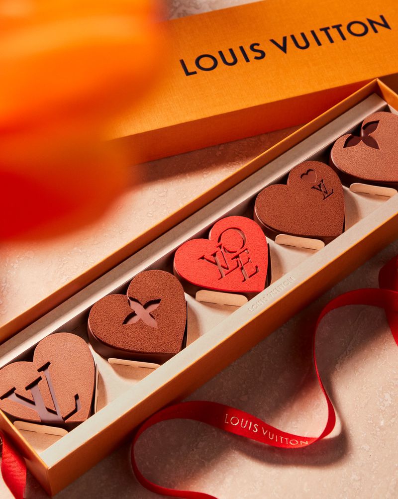 Luxury heart-shaped chocolates in a Louis Vuitton branded box with red ribbon, elegant and decadent, perfect for Valentine's Day gifting.