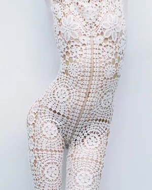 Model wearing a white crochet lace bodysuit against a clean studio background