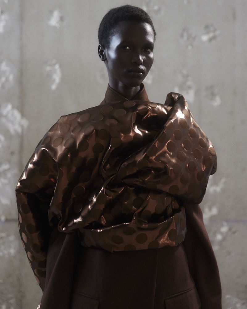 Elegant portrait of a Black woman wearing a bronze dress with polka dots in a studio. The lighting is diffused and flattering.