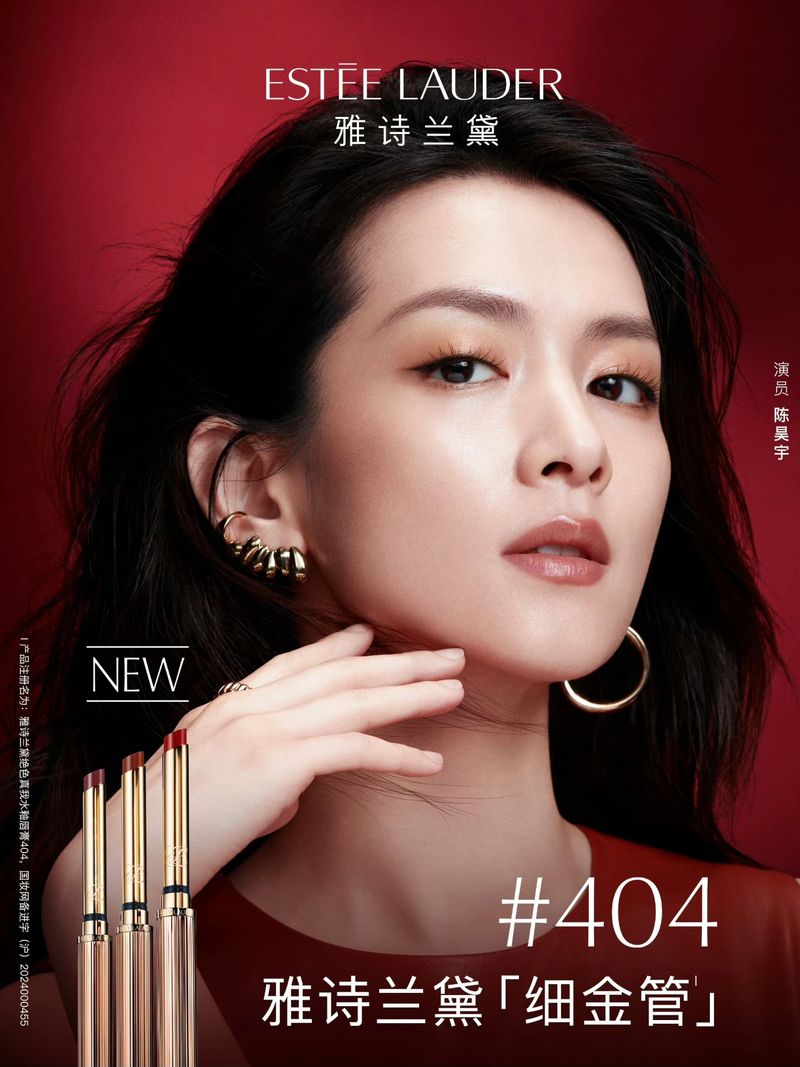 Glamorous beauty ad featuring a sophisticated Asian woman showcasing Estée Lauder lipstick against a rich red backdrop in a beauty shot.