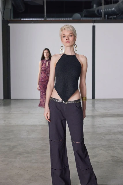 Two female models in contemporary fashion. One wears a black halter top and wide-leg pants, while the other wears a floral dress.