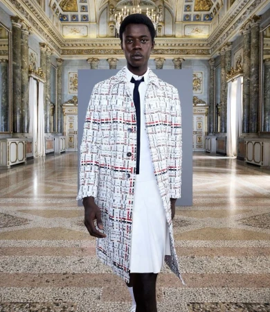 Fashion shot of a slender Black male model wearing a patterned coat, white shirt, and pleated skirt in an ornate marble hall.