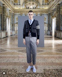 Model wearing a textured dark cardigan, light blue shirt, striped tie, grey trousers, and light blue sneakers