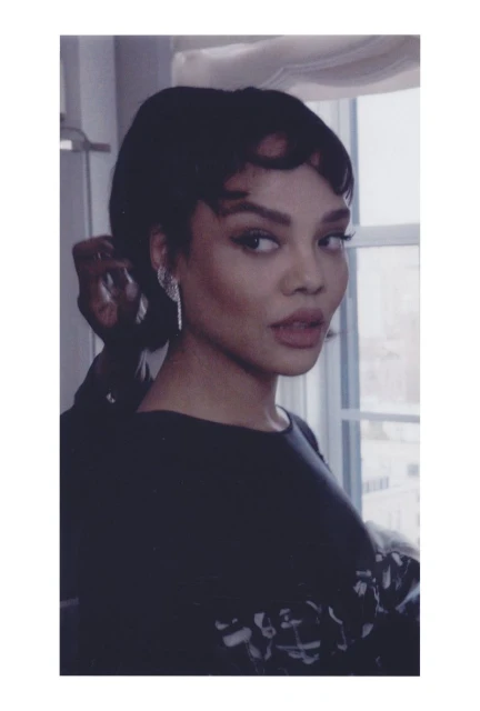 Close-up studio shot of a beautiful adult woman with an elegant updo hairstyle and sparkly earrings, looking over her shoulder.