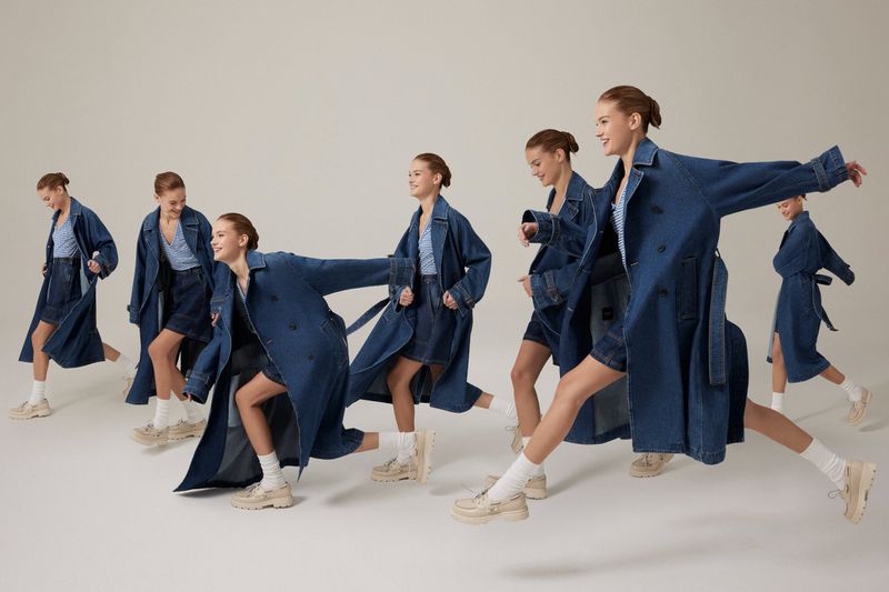 A fashion shot showing a woman wearing a denim trench coat and skirt, captured in a time-lapse series against a light backdrop.