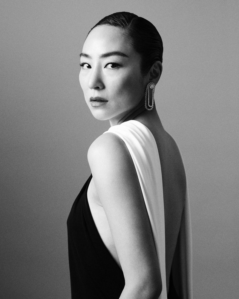 Black and white portrait of a woman with dark hair pulled back, wearing a black dress with a white shawl and decorative earrings.