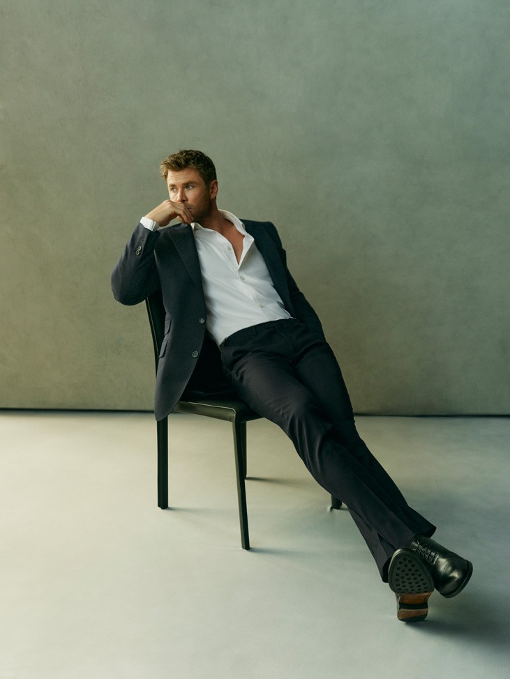 Adult man in suit poses on chair in studio. The subject is fair-skinned with short, light-brown hair and is dressed in business attire.