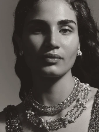 Close-up black and white portrait of Yasmine Alhassan wearing layered diamond necklaces and earrings for Vogue Arabia.