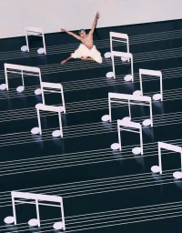 Male ballet dancer in a white feathered tutu leaping across a stage set with oversized white musical notes and staff lines.