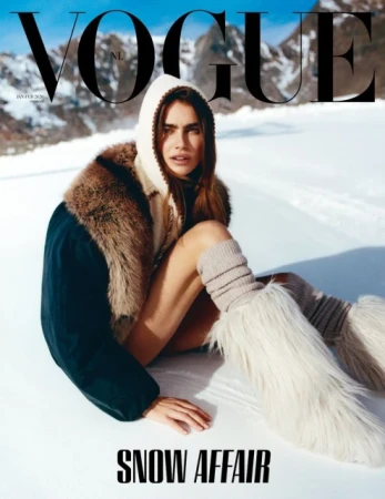 Vogue cover featuring a woman in winter fashion, seated in snow with mountains in the background, wearing a fur-trimmed coat and boots.