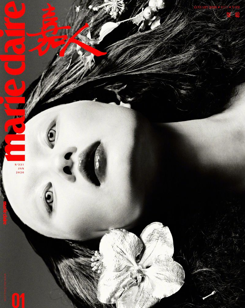 Black and white fashion magazine cover features a woman with dramatic dark hair, fair skin, and a striking white flower hair accessory.