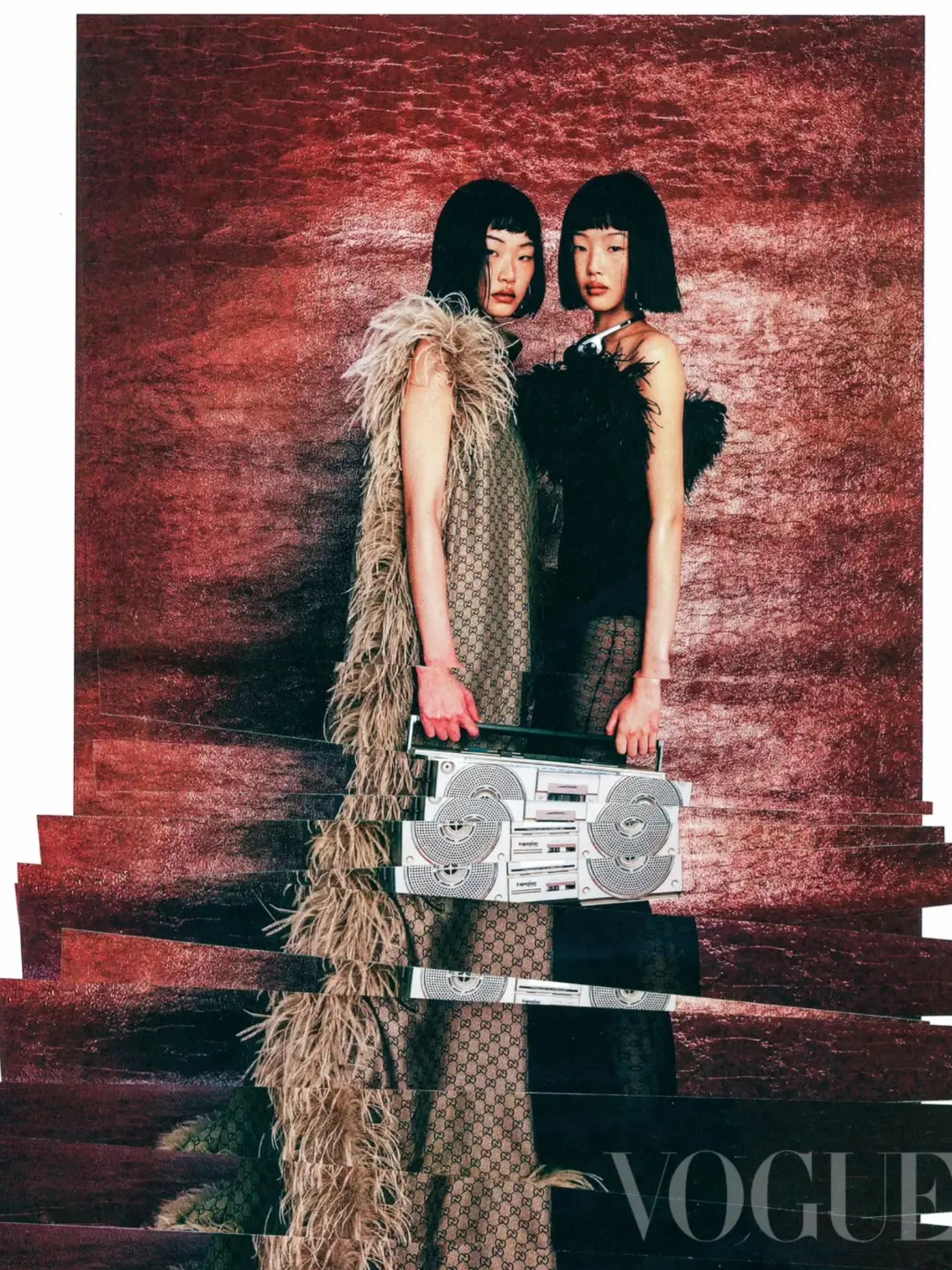 Two women in fashionable outfits pose indoors with a boombox, against a red textured backdrop in a Vogue fashion editorial.