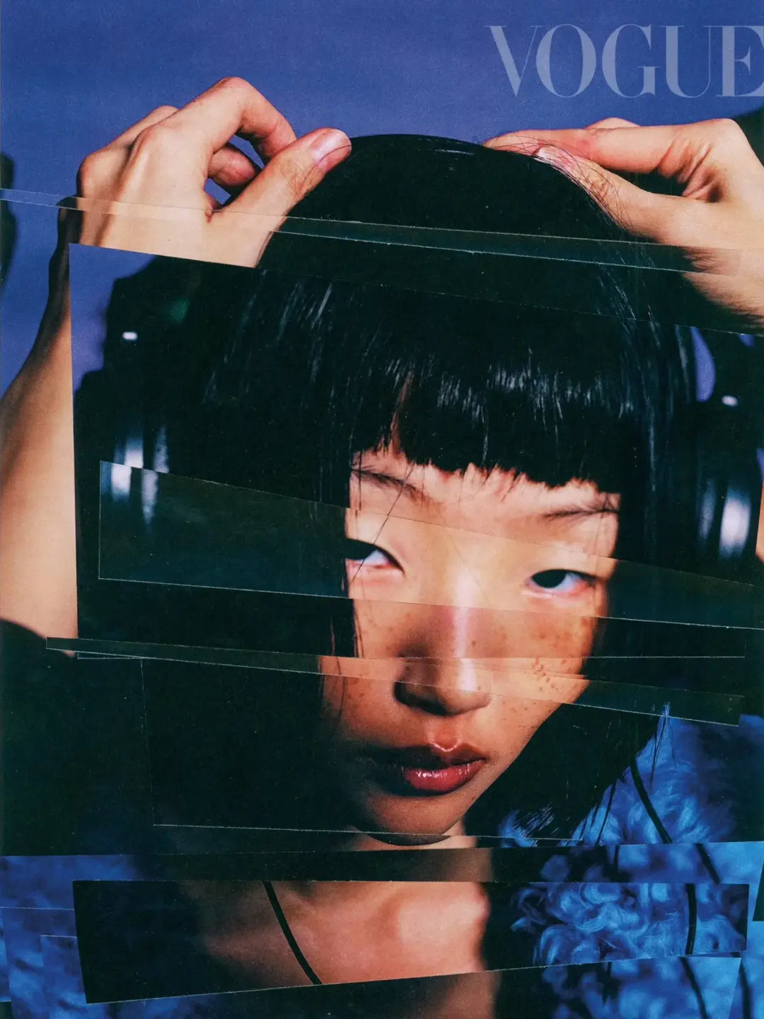 A person with dark hair wearing headphones with hands near their head, and a translucent texture overlay with the Vogue logo at top.