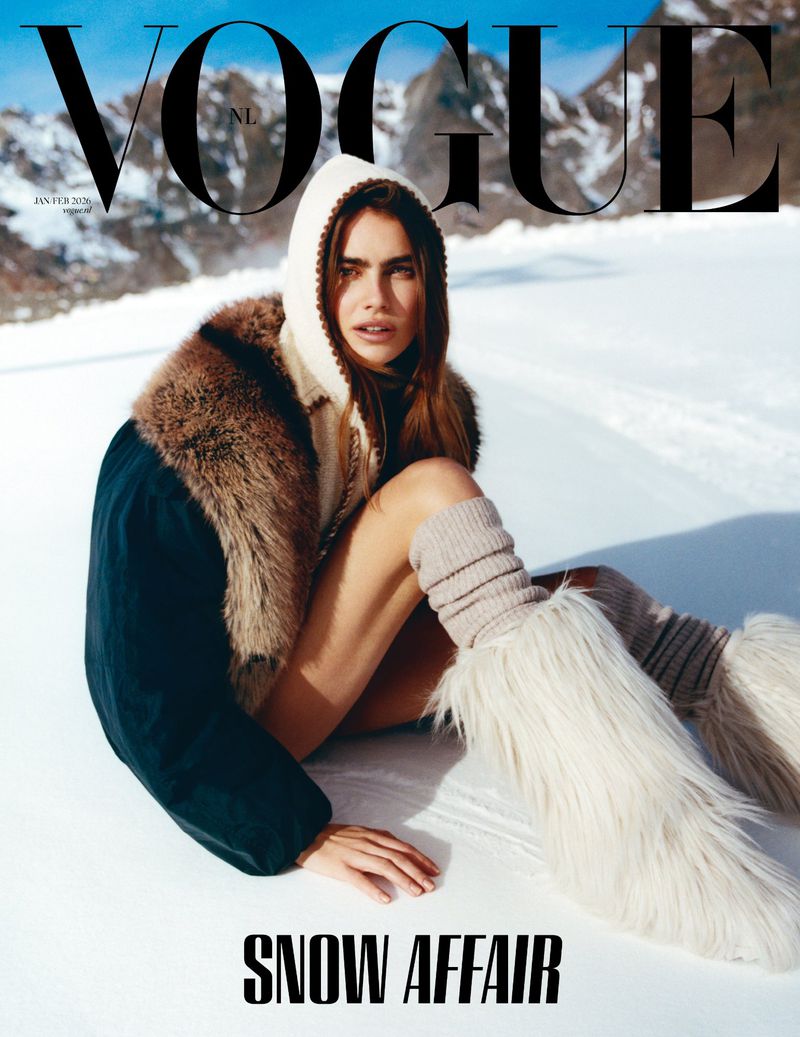 Vogue magazine cover featuring a model sitting in snow wearing a furry hooded jacket and furry boots, with mountains in the background.