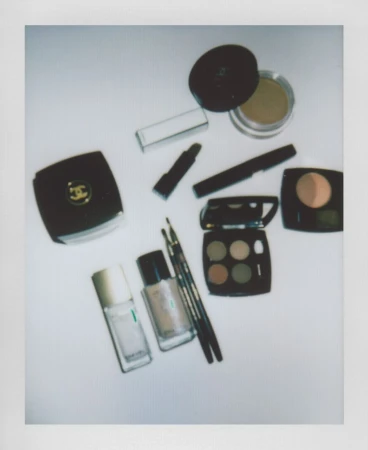 Overhead shot of Chanel makeup products including eyeshadow palettes, lipsticks, and nail polish arranged on a white surface.