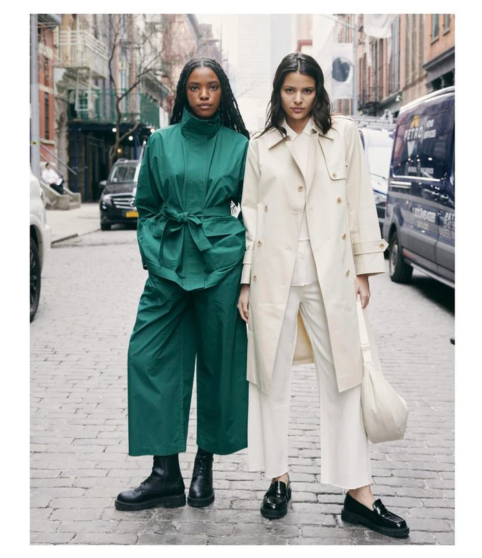 Two female models standing on a cobblestone street wearing Uniqlo C collection outerwear and trousers