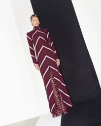 Model standing against a high-contrast black and white backdrop wearing a patterned long-sleeve knit maxi dress